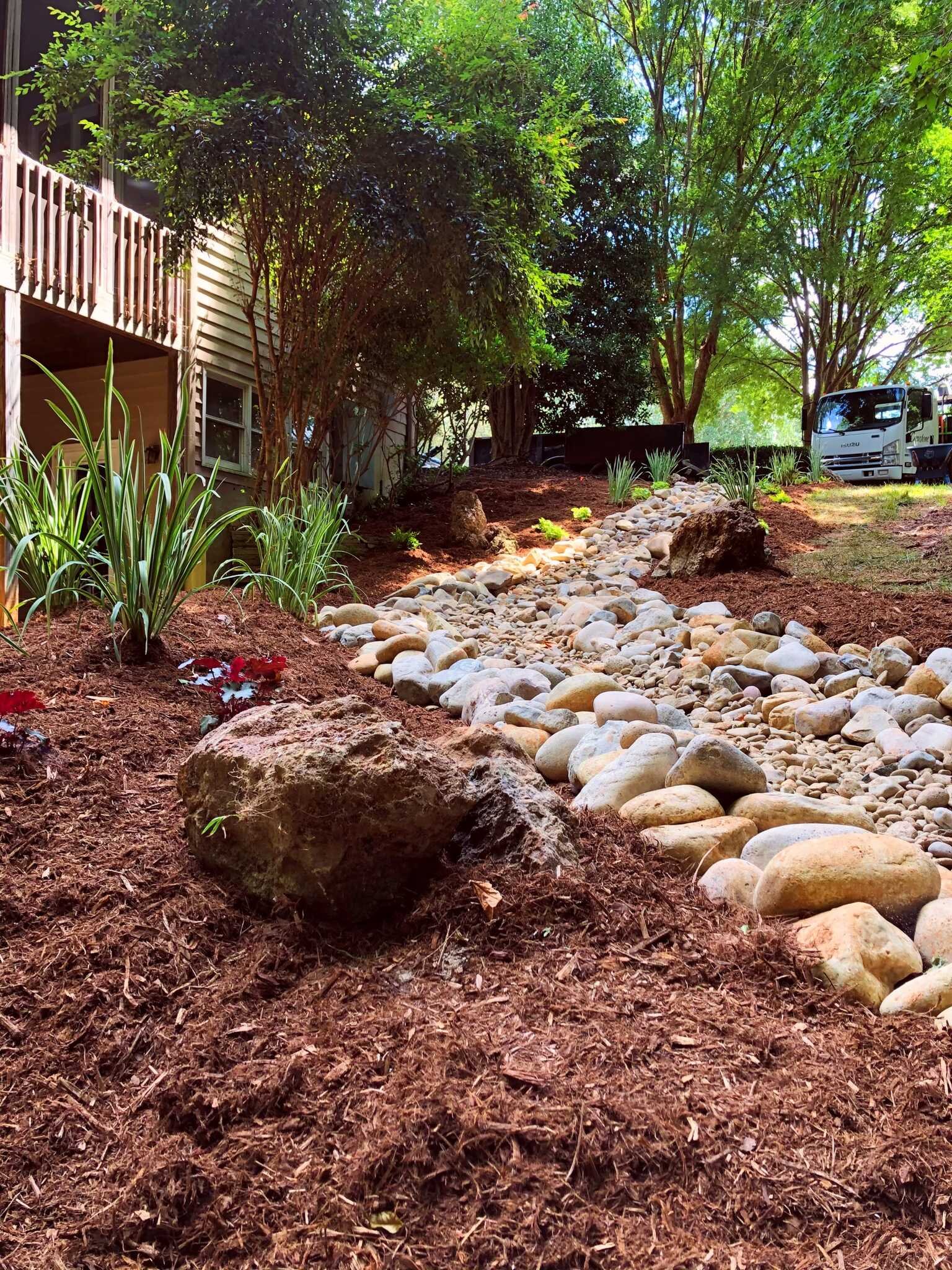 Dry creek bed built with river rock to carry runoff across a Wake County yard