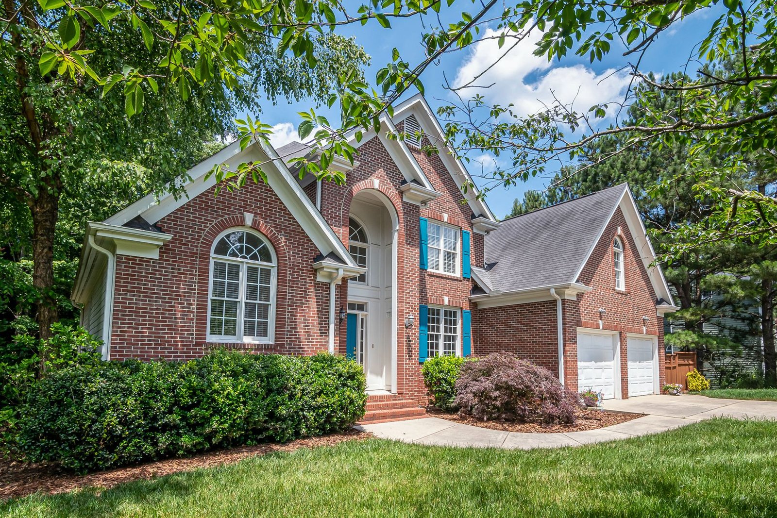 Brick house surrounded by mature shrubs and greenery